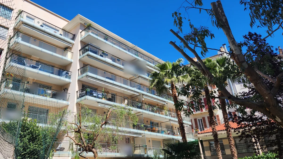 Façade arrière du Jardin Pastorelli, 23 rue Pastorelli à Nice : terrasses filantes vitrées sur plusieurs niveaux, palmiers et jardin intérieur paysager