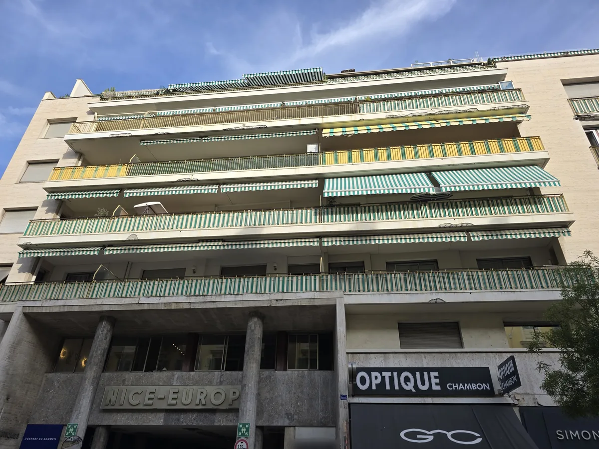 Ensemble Nice-Europe à Nice, façade rue de l'Hôtel-des-Postes : terrasses filantes à stores rayés, colonnes et inscription « Nice-Europe »