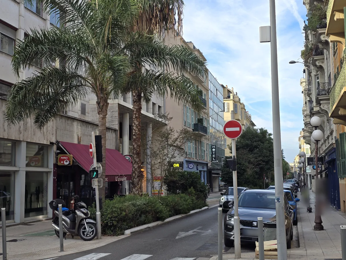 Rue Pastorelli à Nice vers l'avenue Jean-Médecin : palmiers, immeuble Nice-Europe des années 1960 et façades niçoises à balcons ouvragés