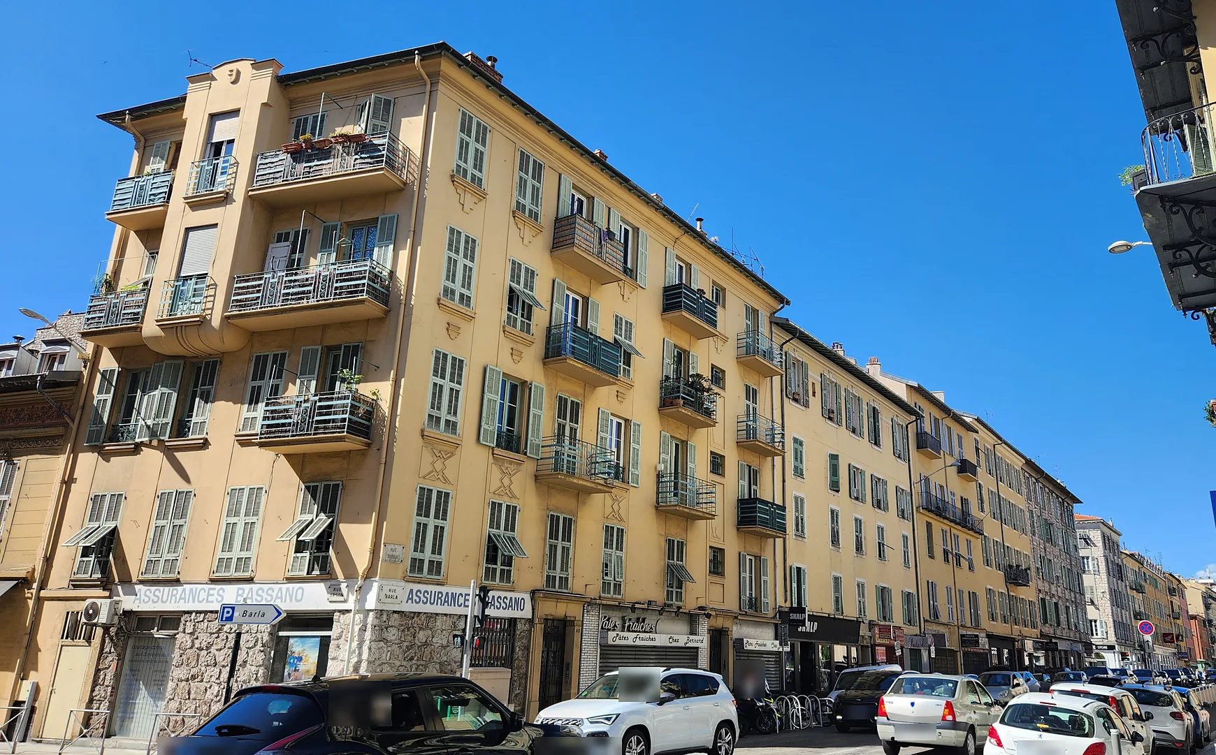 Front d'immeubles anciens ocre à balcons et volets verts, à l'angle de la rue Arson et de la rue Barla à Nice